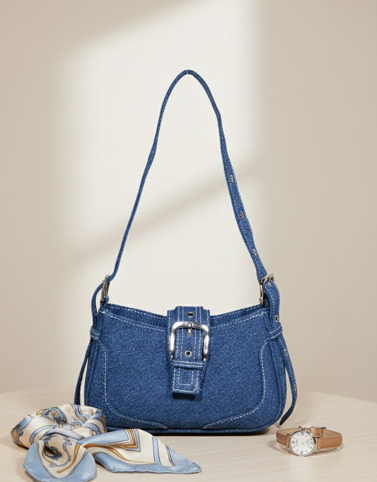 Blue denim handbag with silver buckle on table, styled with scarf and leather strap watch