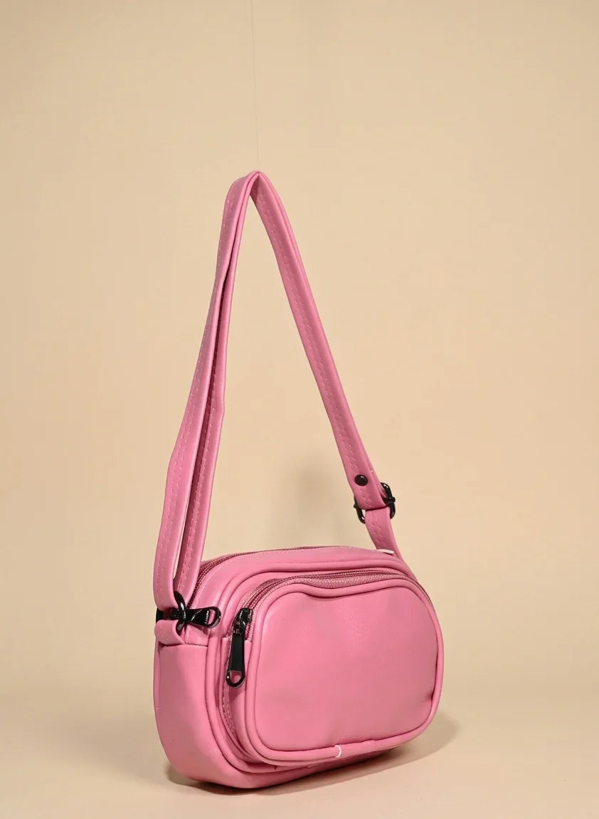 Stylish pink shoulder handbag with zip pocket and adjustable strap on beige background