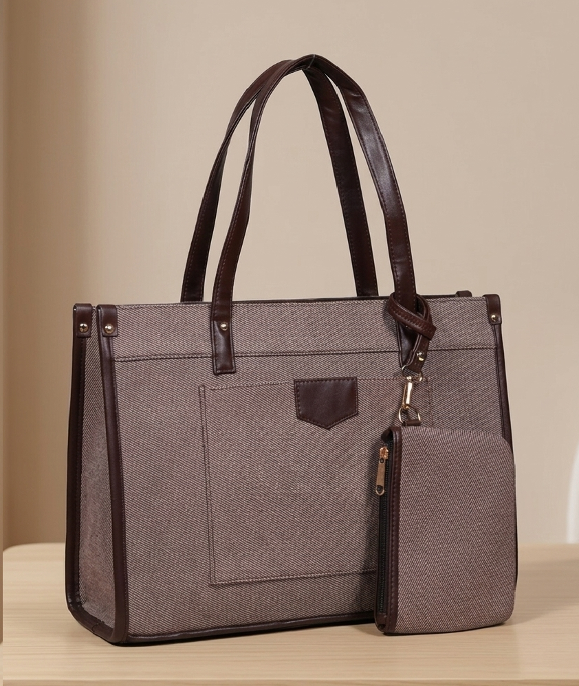 Taupe structured handbag with brown leather trim and matching zip pouch on beige table