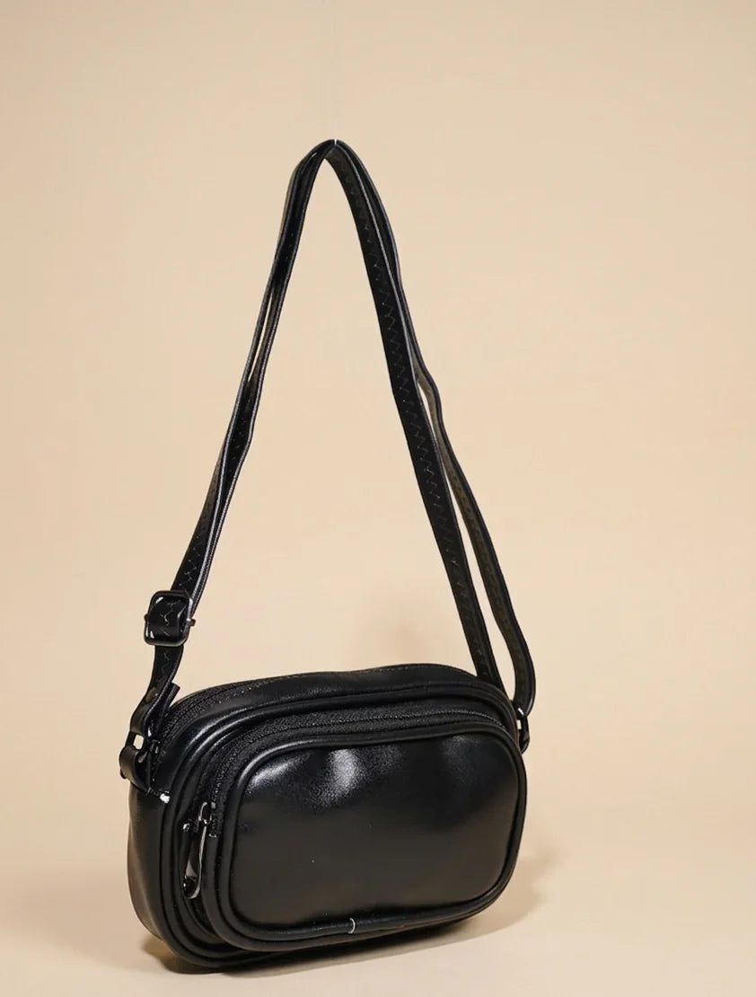 Sleek black leather crossbody handbag with adjustable strap on a neutral background