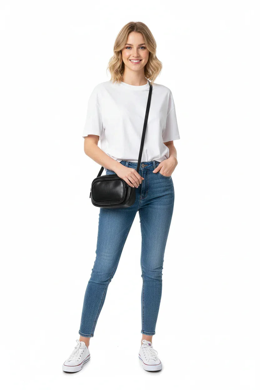 Woman modeling a black leather crossbody handbag with casual jeans and white t-shirt