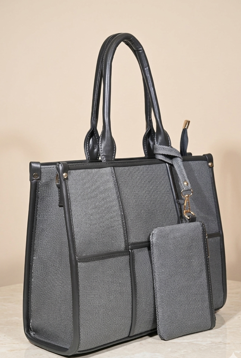 Elegant gray tote handbag with black leather handles and matching pouch, on neutral background