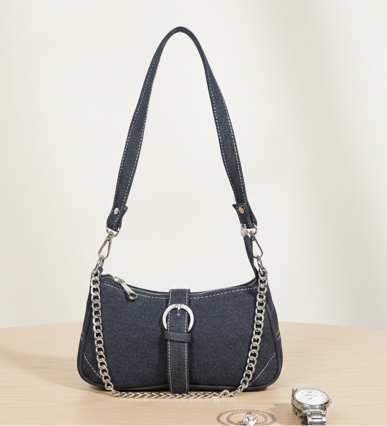 Stylish black denim handbag with chain strap and silver buckle on wooden table