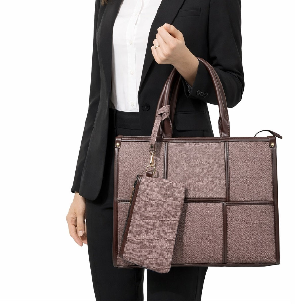 Woman in black suit holding large textured taupe handbag with matching pouch, white background