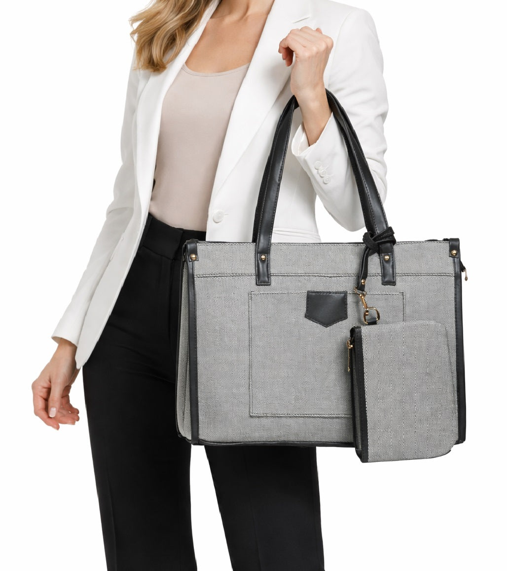 Woman in white blazer holding a gray tote handbag with black trim and matching pouch